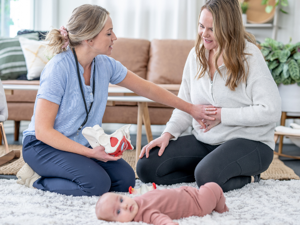 A woman experiencing postpartum recovery, with her baby on the floor, highlighting the journey of rebuilding strength and confidence.