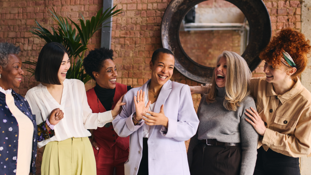 A group of diverse women laughing and enjoying a conversation, symbolizing confidence, positivity, and wellbeing.